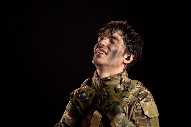 Free photo portrait of relieved young soldier in uniform on a dark wall