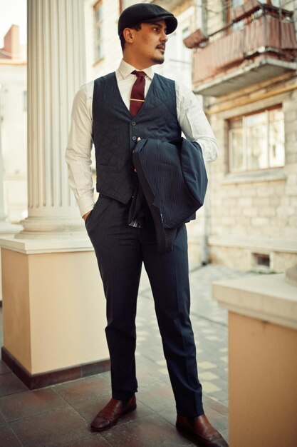 Portrait of retro 1920s english arabian business man wearing dark suit tie and flat cap