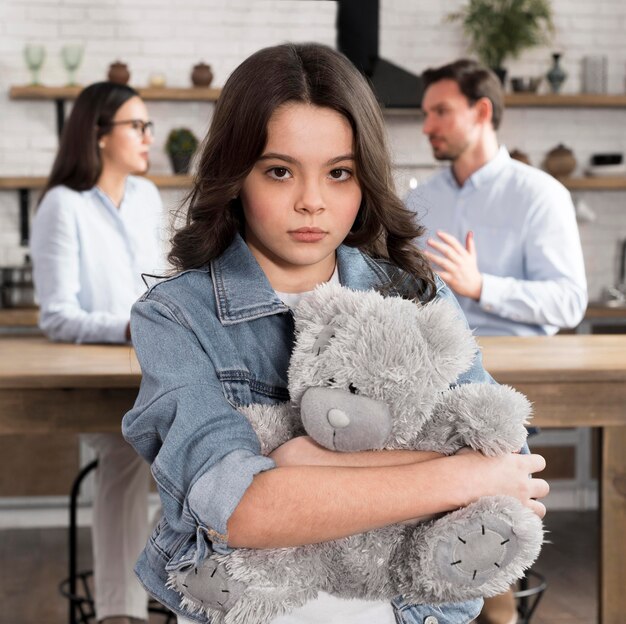 Portrait of sad daughter holding teddy bear