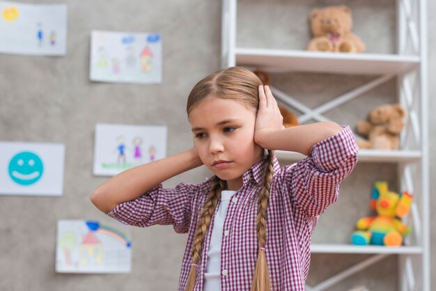 Portrait of sad girl covering her ears with two hands