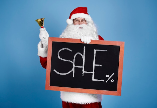 Free photo portrait of santa claus holding blackboard and bell