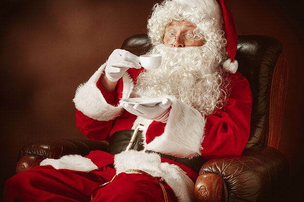 Portrait of Santa Claus in red costume with coffee cup