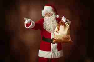 Free photo portrait of santa claus in red costume with gift bag