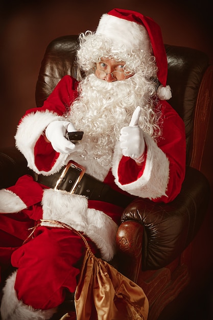 Portrait of Santa Claus in red costume with TV remote control