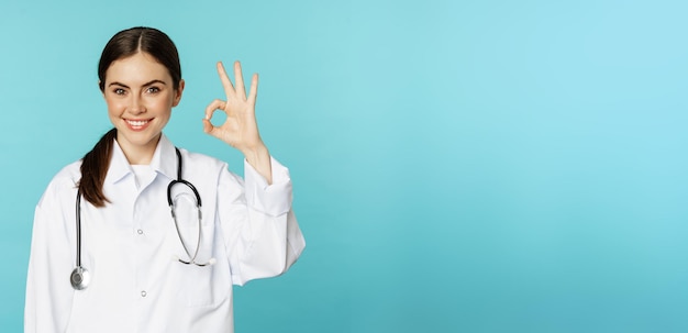 Free Photo portrait of satisfied smiling medical worker woman doctor showing okay ok zero no problem gesture excellent sign standing pleased over torquoise background