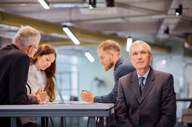 Free photo portrait of senior businessman with his team in the office