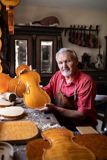 Portrait of senior carpenter in his old-fashion workshop making violins music instrument for academy of arts