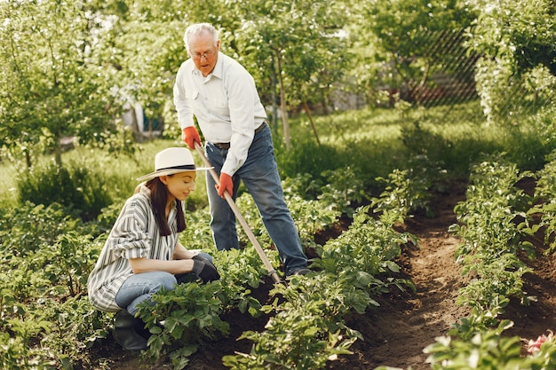 Free photo portrait of senior man in a hat gardening with granddaugher