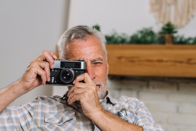 Free photo portrait of senior man taking photo from camera