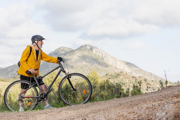 Portrait senior man with bike on mountain