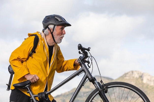 Portrait senior man with bike on mountain