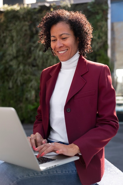 Portrait of senior woman in professional blazer outdoors and laptop