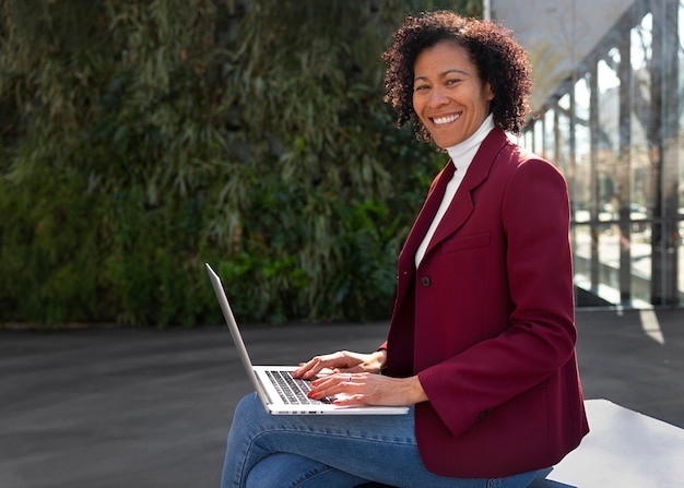 Portrait of senior woman in professional blazer outdoors and laptop