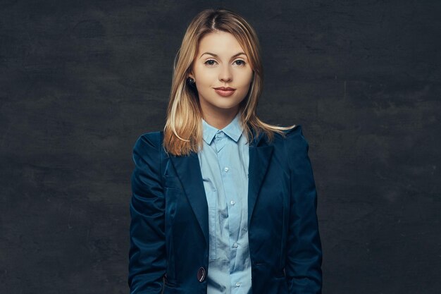 Portrait of a sensual blonde business woman dressed in a formal suit and blue shirt. Isolated on a dark background.