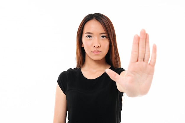 Portrait of serious asian woman standing with outstretched hand showing stop gesture