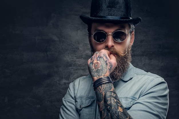 Portrait of serious, bearded male in sunglasses and cylinder hat.