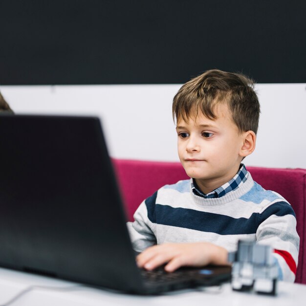 Portrait of a serious boy using laptop in the classroom