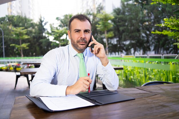 Portrait of serious businessman talking to partner on phone