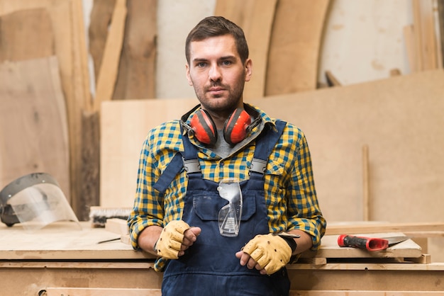 Free photo portrait of serious male carpenter with ear defender around his neck