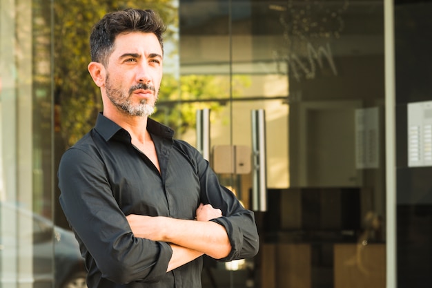 Portrait of serious man in black shirt standing in front of closed door