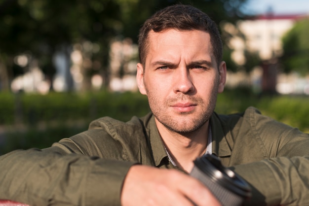 Free photo portrait of serious young man looking at camera at park