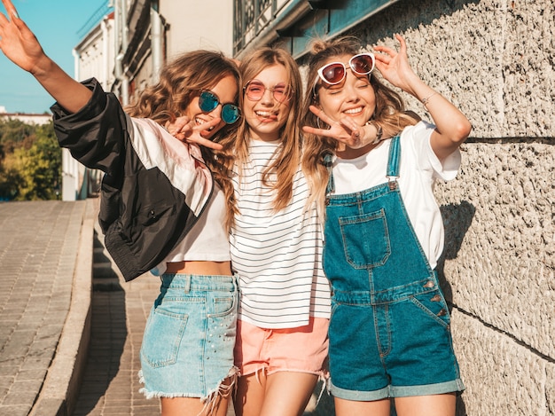 Portrait of  Sexy carefree women posing near wall in the street.Positive models having fun in sunglasses