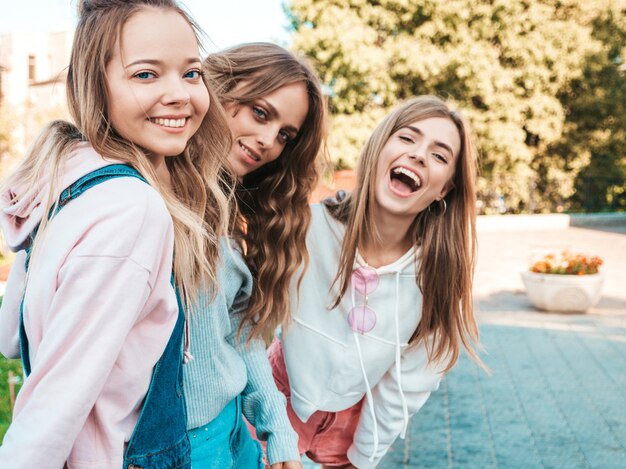 Portrait of  Sexy carefree women posing on the street background.Positive models having fun in sunglasses.Hugging