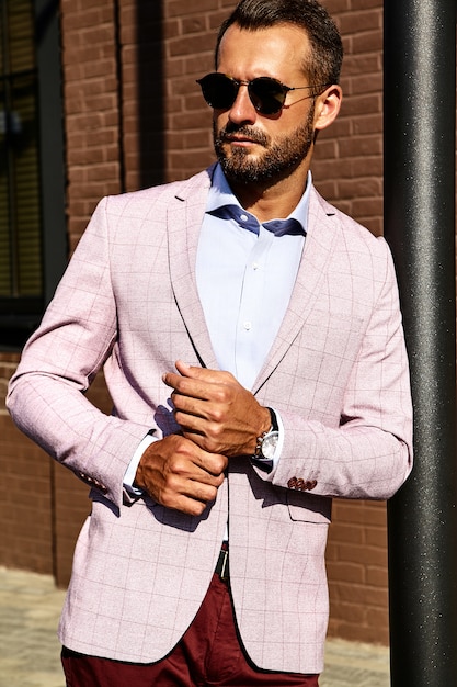 Free Photo portrait of sexy handsome fashion businessman model dressed in elegant suit posing near brick wall on the street background. metrosexual