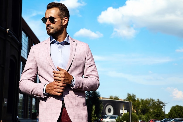 Portrait of sexy handsome fashion businessman model dressed in elegant suit posing on street background. Metrosexual