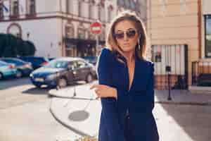 Free photo portrait of sexy stylish woman walking in street in blue suit wearing sunglasses on sunny autumn day