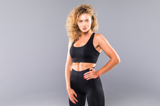 Free Photo portrait of sexy young woman with her hands on hips. fitness female with muscular body ready wearing hand gloves for workout on grey wall