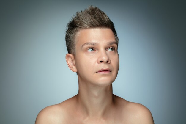 Portrait of shirtless young man isolated on grey studio wall.