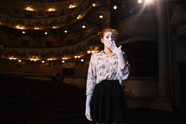 Portrait of shocked female mime standing in auditorium