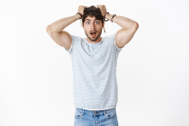 Free photo portrait of shocked guy in stupor dropping jaw astomished pulling hair out of head being impressed deeply standing stunned and anxious