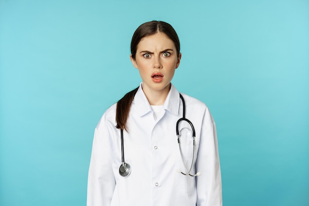 Free photo portrait of shocked woman doctor female hospital intern in white coat looking concerned and confused...