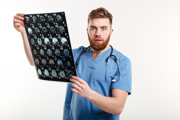 Free photo portrait of a shocked young medical doctor holding ct scan