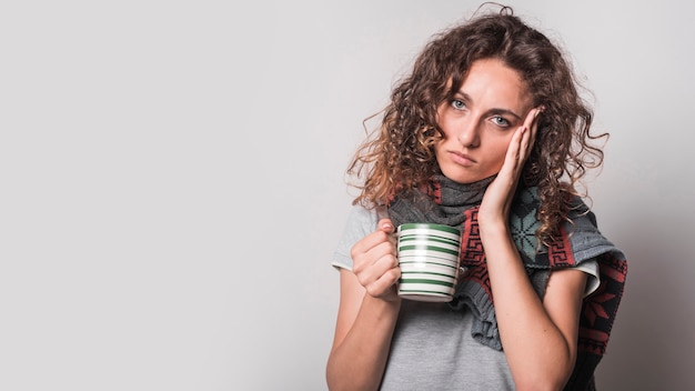 Free Photo portrait of sick woman holding coffee mug against gray background