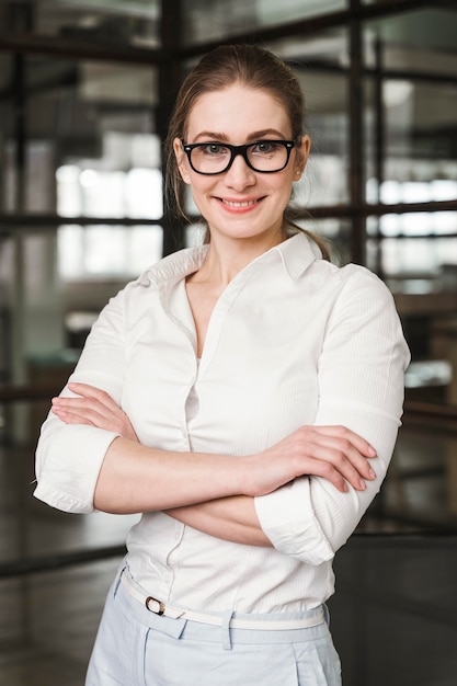 Free Photo portrait of smiley businesswoman indoors with arms closed