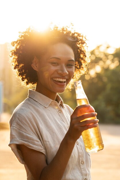 Portrait of smiley happy woman outdoors in the sunlight having beer