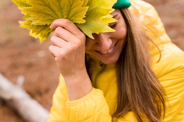 Portrait of smiley woman holding autumn leaves outdoors