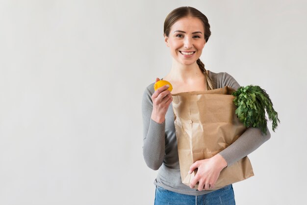 Portrait of smiley woman holding paper bag with groceries