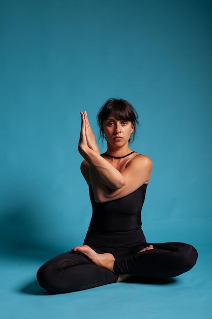 Portrait of smiling adult trainer standing in padmasana position holding arms in crossed position practicing spiritual meditation. Athletic person working at healthy lifestyle stretching body muscles