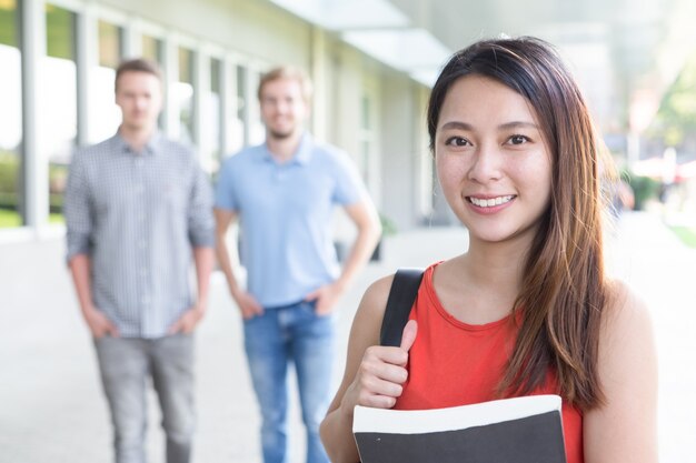 Portrait of smiling Asian female student with book