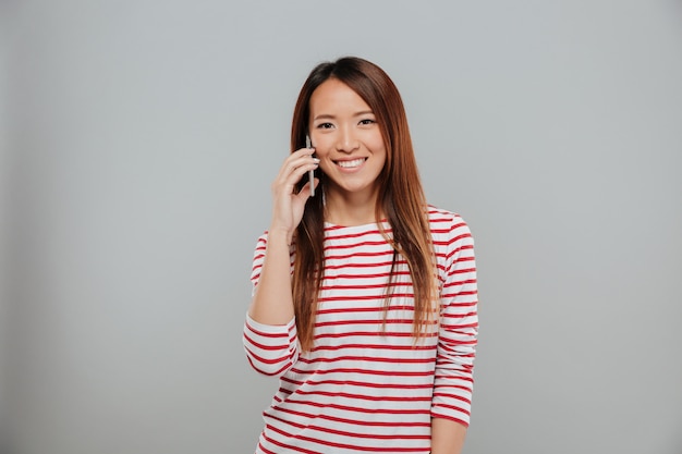 Portrait of a smiling asian girl talking on mobile phone