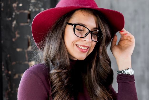 Portrait of a smiling beautiful young woman with pink hat and black eyeglasses