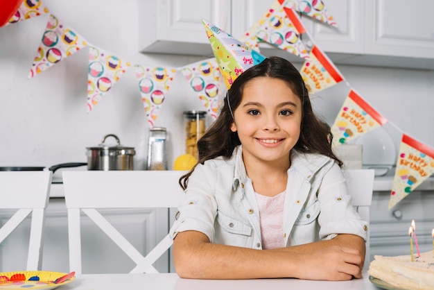 Free Photo portrait of a smiling birthday girl wearing party hat on head looking at camera