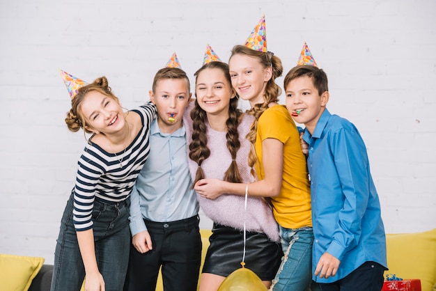 Free photo portrait of a smiling birthday teenage girl posing with her friends wearing party hat