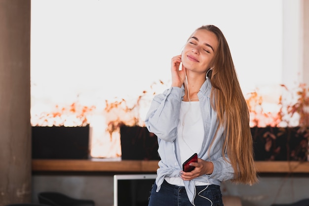 Free photo portrait of smiling blonde woman holding phone