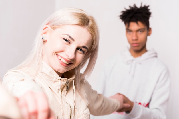 Free photo portrait of smiling blonde young woman holding hands of her boyfriend