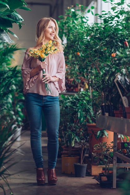 Free photo portrait of smiling blonde young woman holding yellow flower